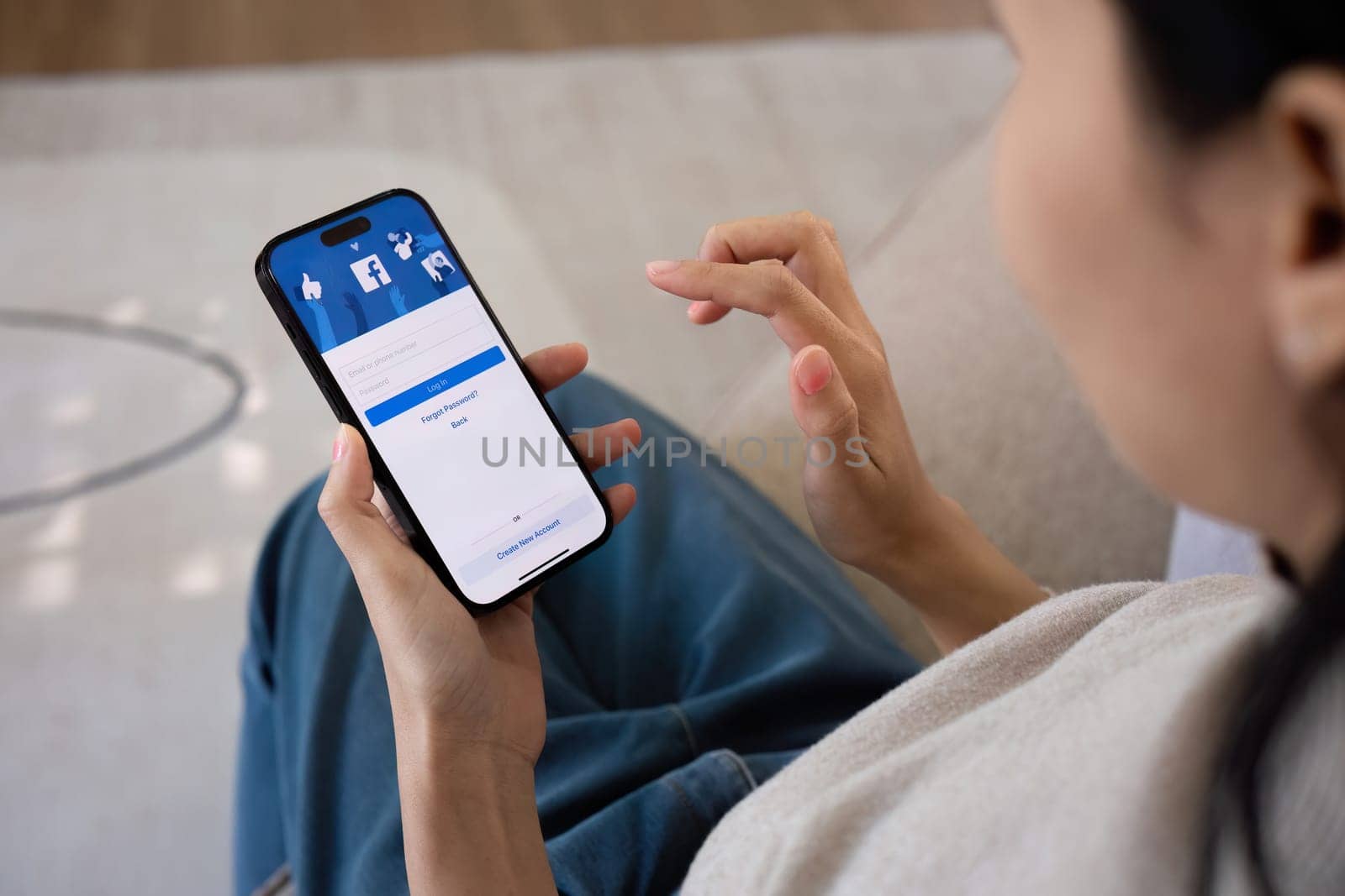 CHIANG MAI, THAILAND - FEB 27 ,2024: Woman holding Iphone 14 with Facebook application on the screen. Facebook is a popular online social networking service..