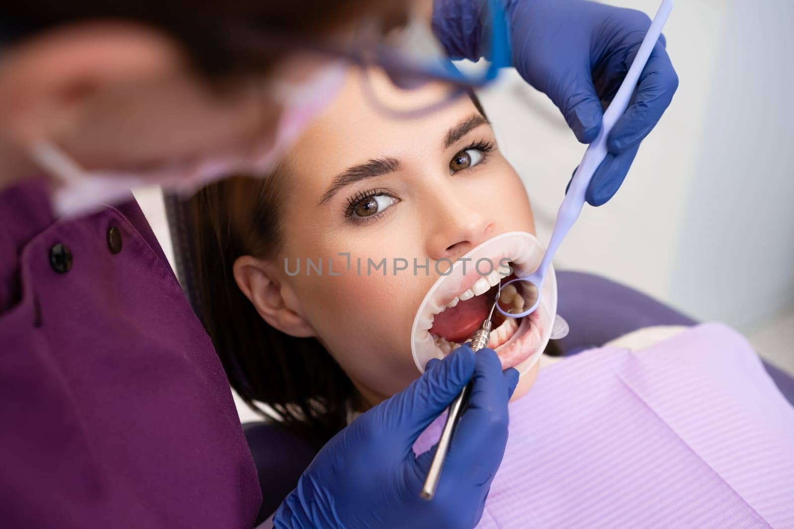 Dentist uses dental tools and mirror to check the teeth of woman patient by vladimka