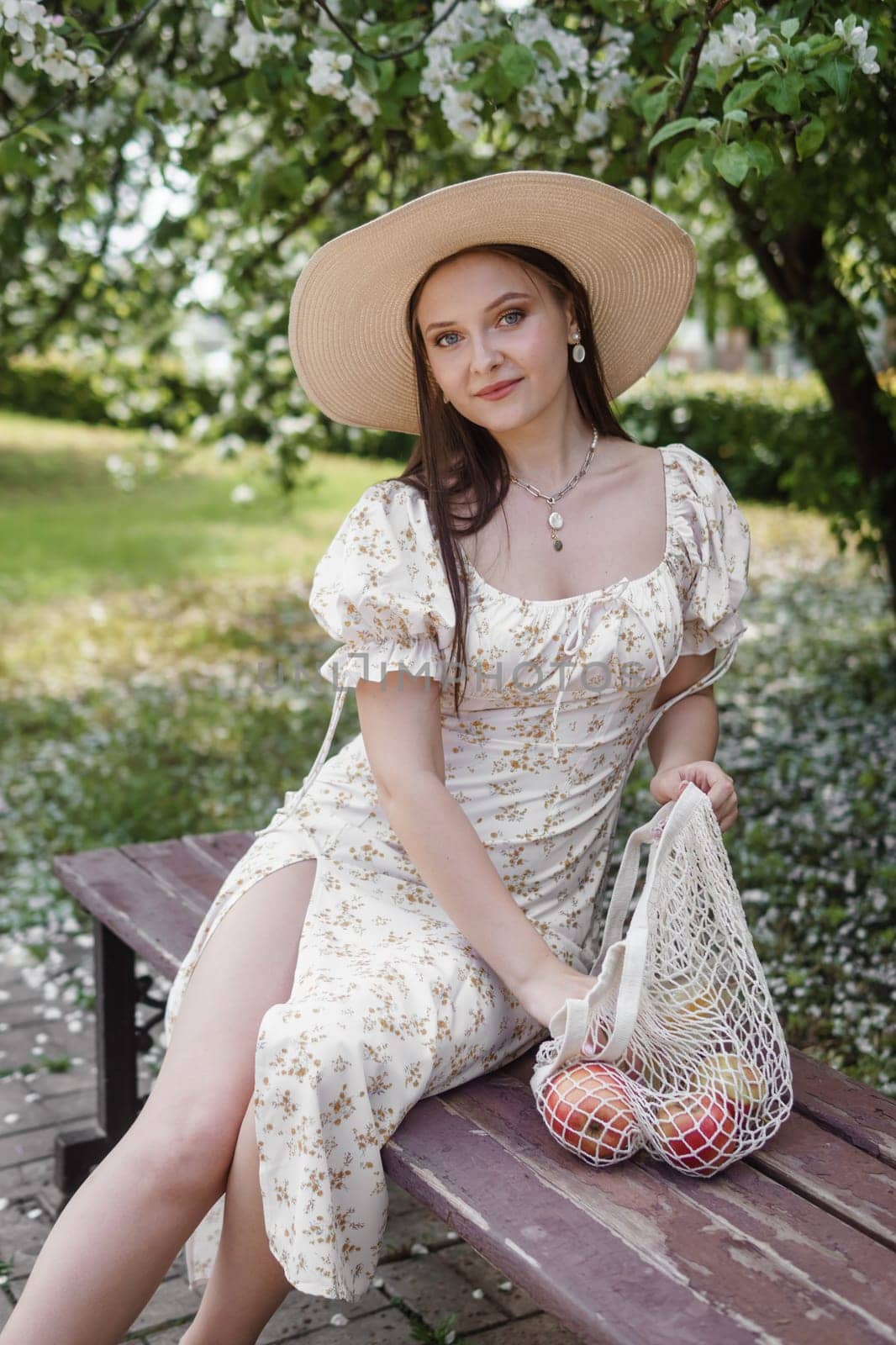 An attractive long-haired woman walks in the spring in the park of blooming apple trees. Spring portrait of a woman