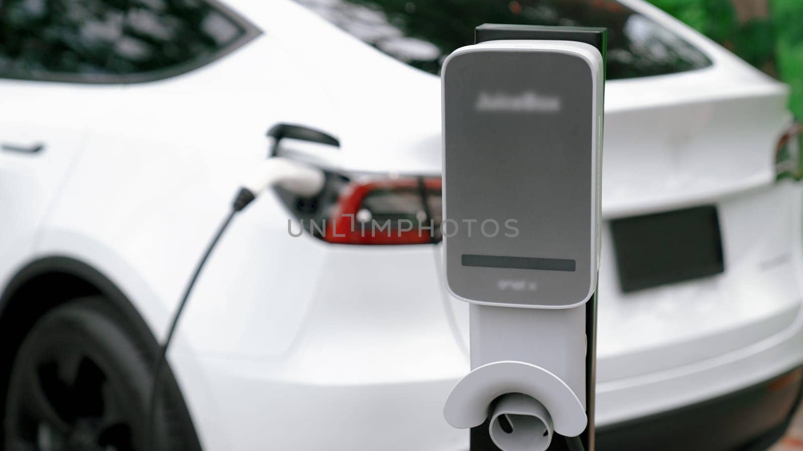 EV electric vehicle recharging battery from EV charging station in national park or outdoor forest scenic. Natural protection with eco friendly EV car travel in the summer woods. Exalt