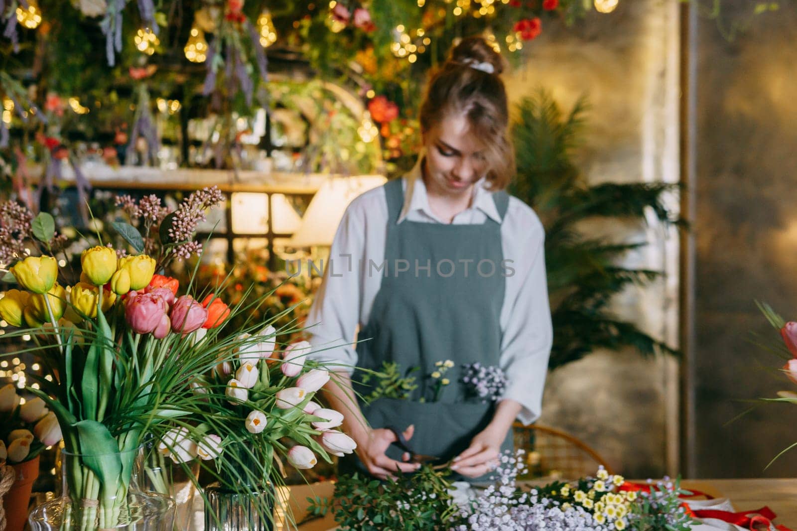 A woman in her florist shop collects bouquets of flowers. The concept of a small business. Bouquets of tulips for the holiday on March 8