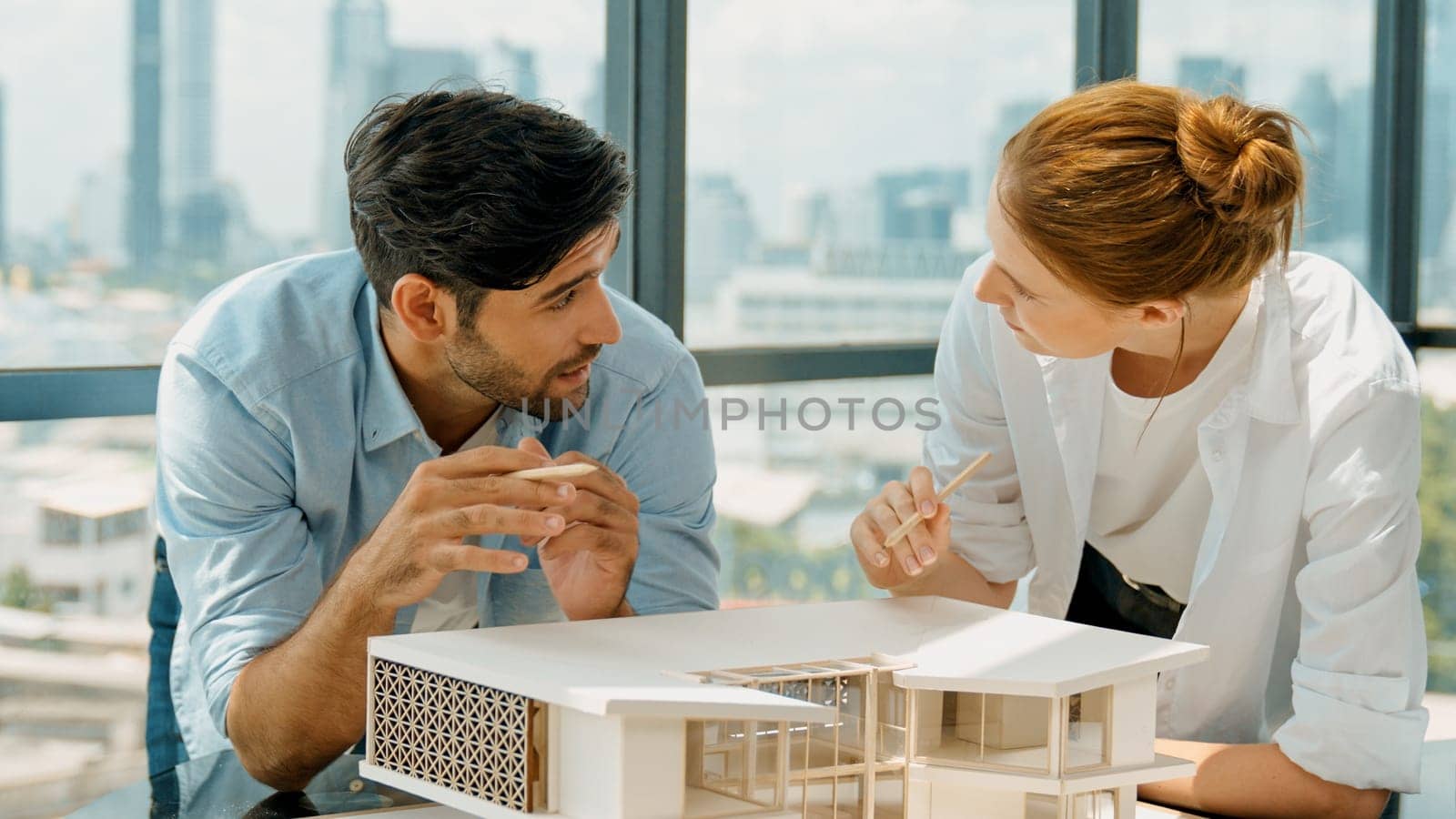 Cooperative architect engineer team working together to measure house model by using pencil. Successful caucasian interior designer team inspect architectural model construction. Design. Tracery