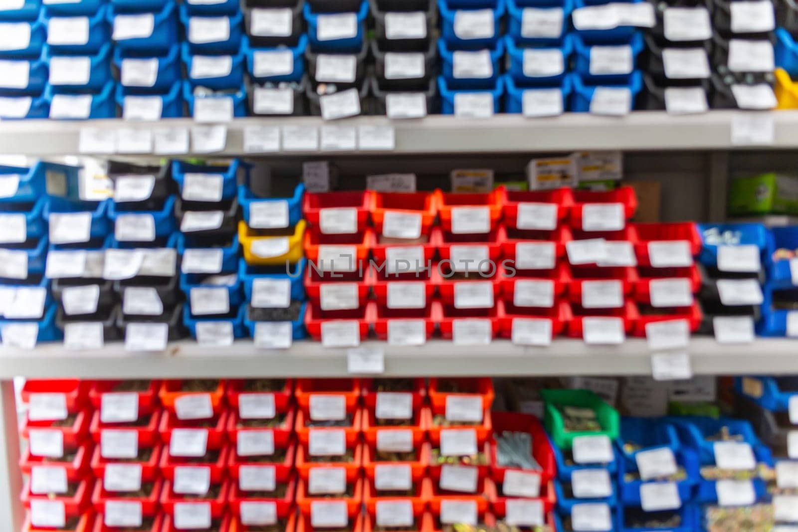 Blurred background with shelves with a large number of trays with fasteners, accessories and small consumables in the building materials store