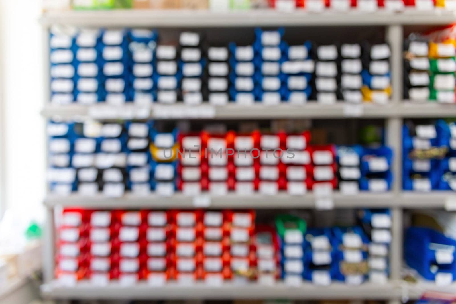 Blurred background with shelves with a large number of trays with fasteners, accessories and small consumables in the building materials store