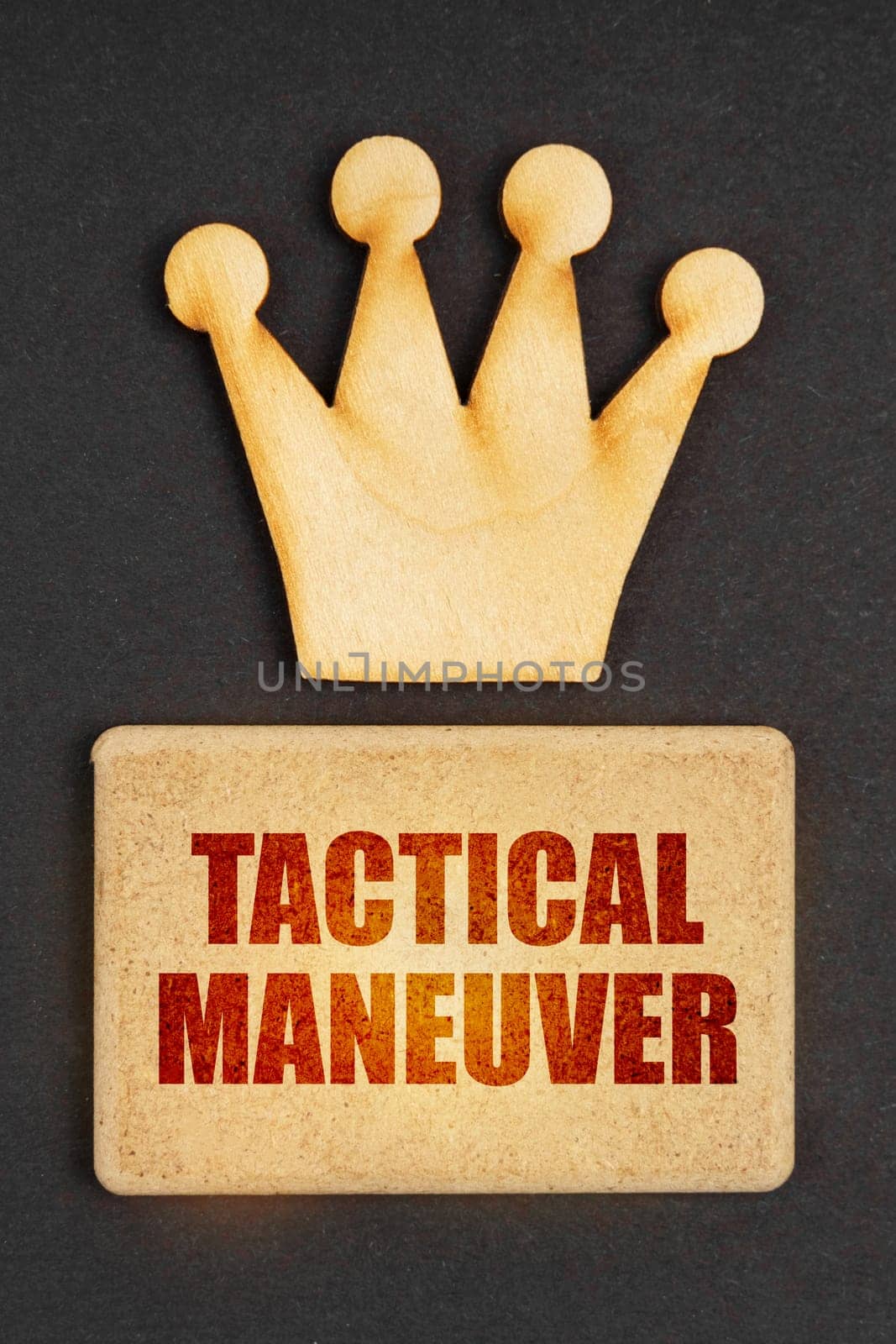 Business concept. On a black background there is a wooden crown of the leader and a sign with the inscription - Tactical Maneuver
