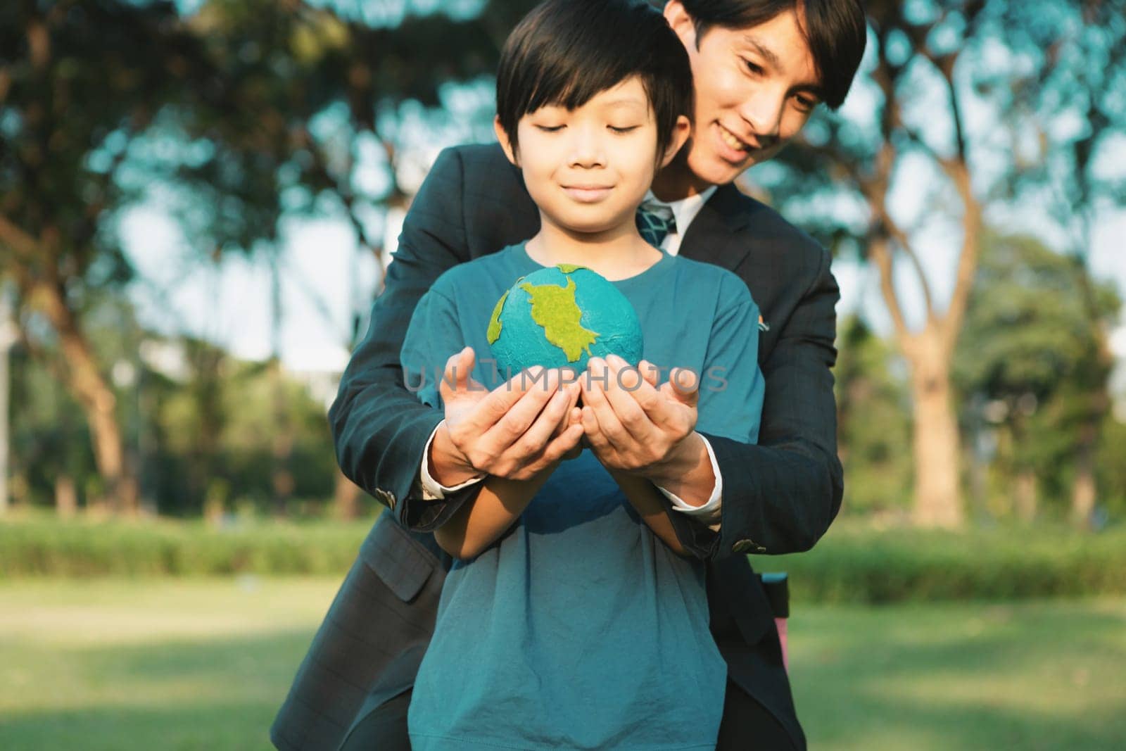 Asian boy and businessman holding planet Earth together as Earth day concept as corporate social responsible to make greener environmental protection for sustainable future generation. Gyre