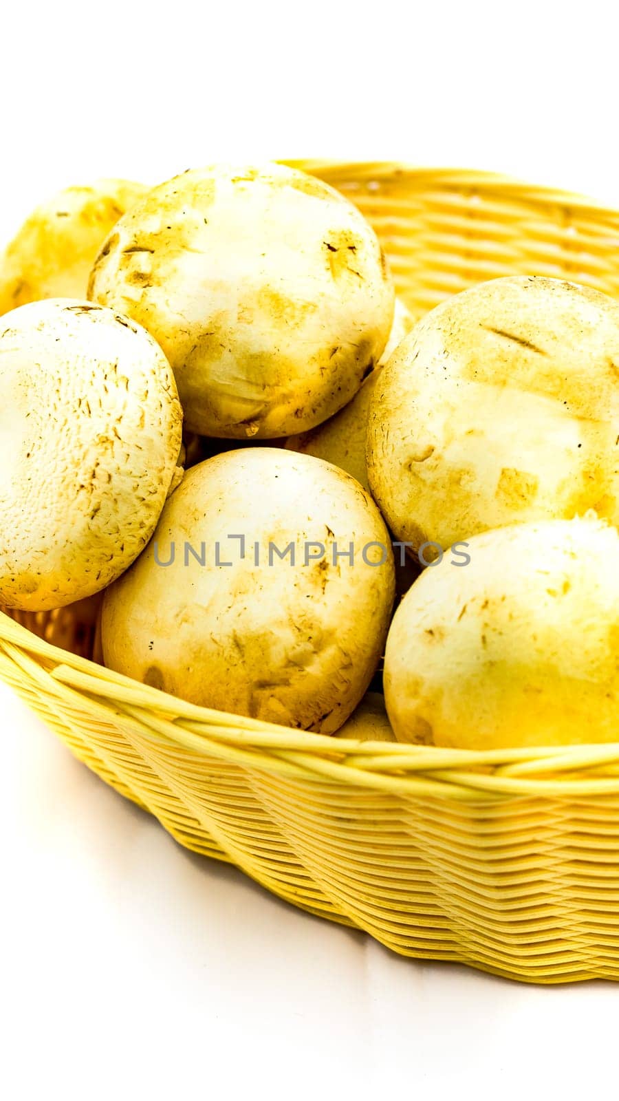 Fresh champignons, champignon mushrooms in wicker basket isolated by vladispas
