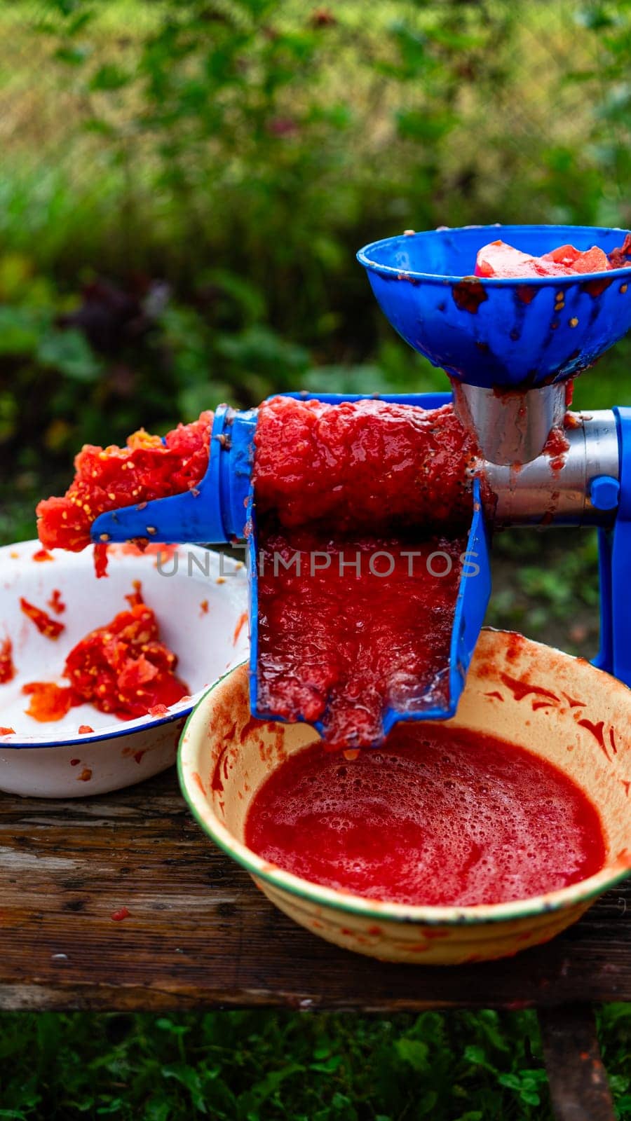 Close up photo of a manual tomato-grinder. Fresh tomatoes, for preparing handmade tomato paste.