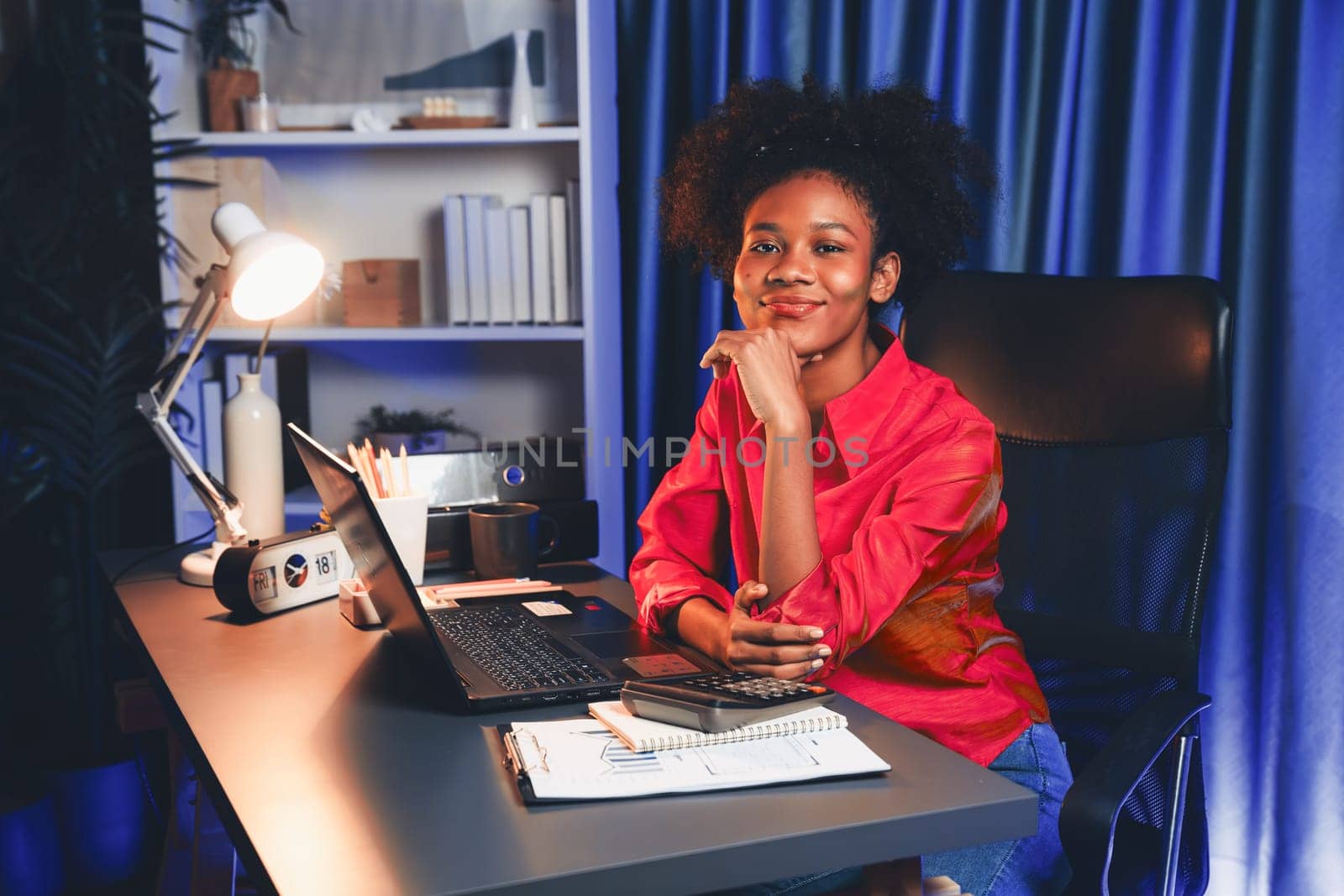 African woman blogger wearing pink shirt with happy face, looking on screen laptop with valued achievement project or get scholarship. Concept of cheerful expression work from home. Tastemaker.