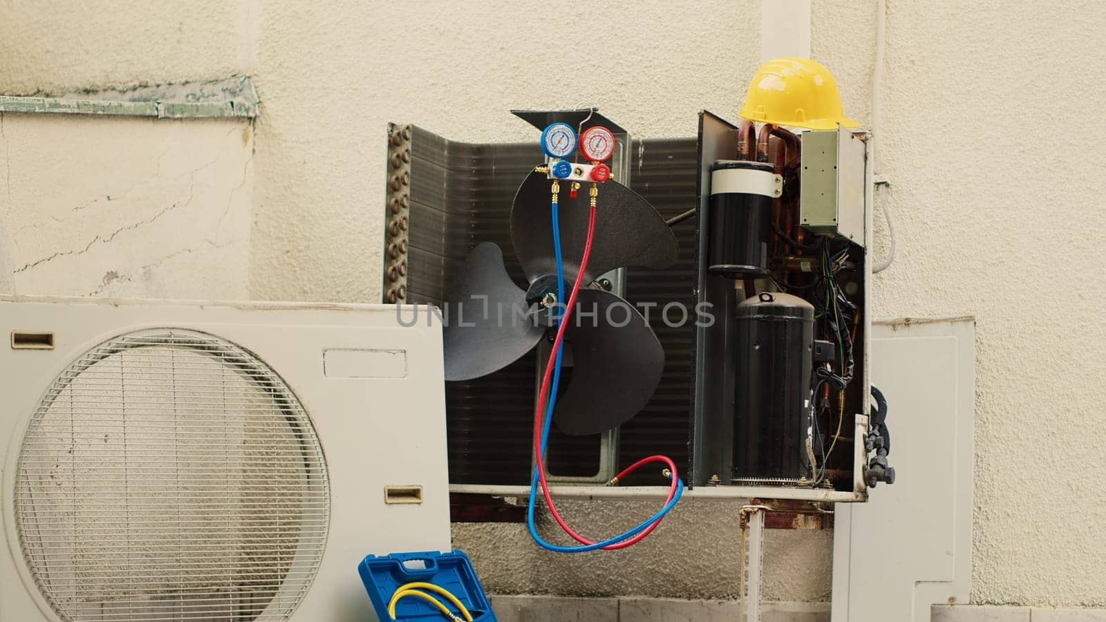 Faulty condenser with protection cover removed in need of mending, with defective electric internal parts. External air conditioner not functioning anymore, ready to be repaired, zoom in tilt up shot