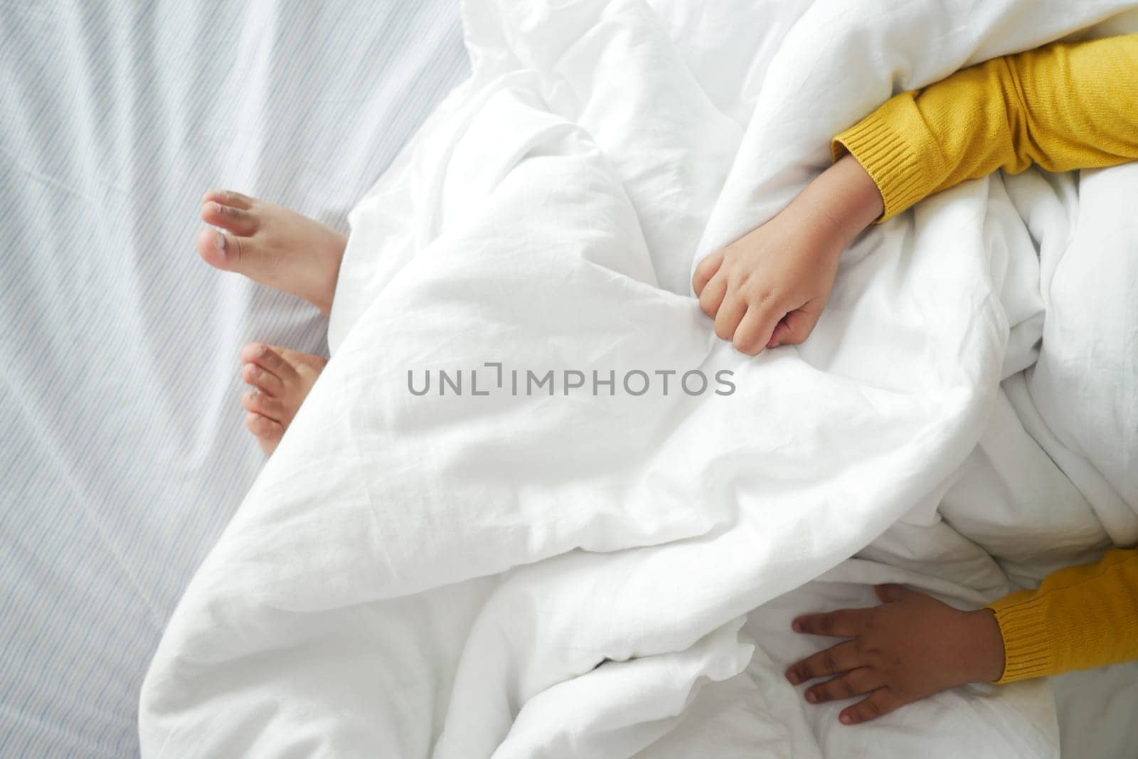 Bare feet of a child on white bed by towfiq007