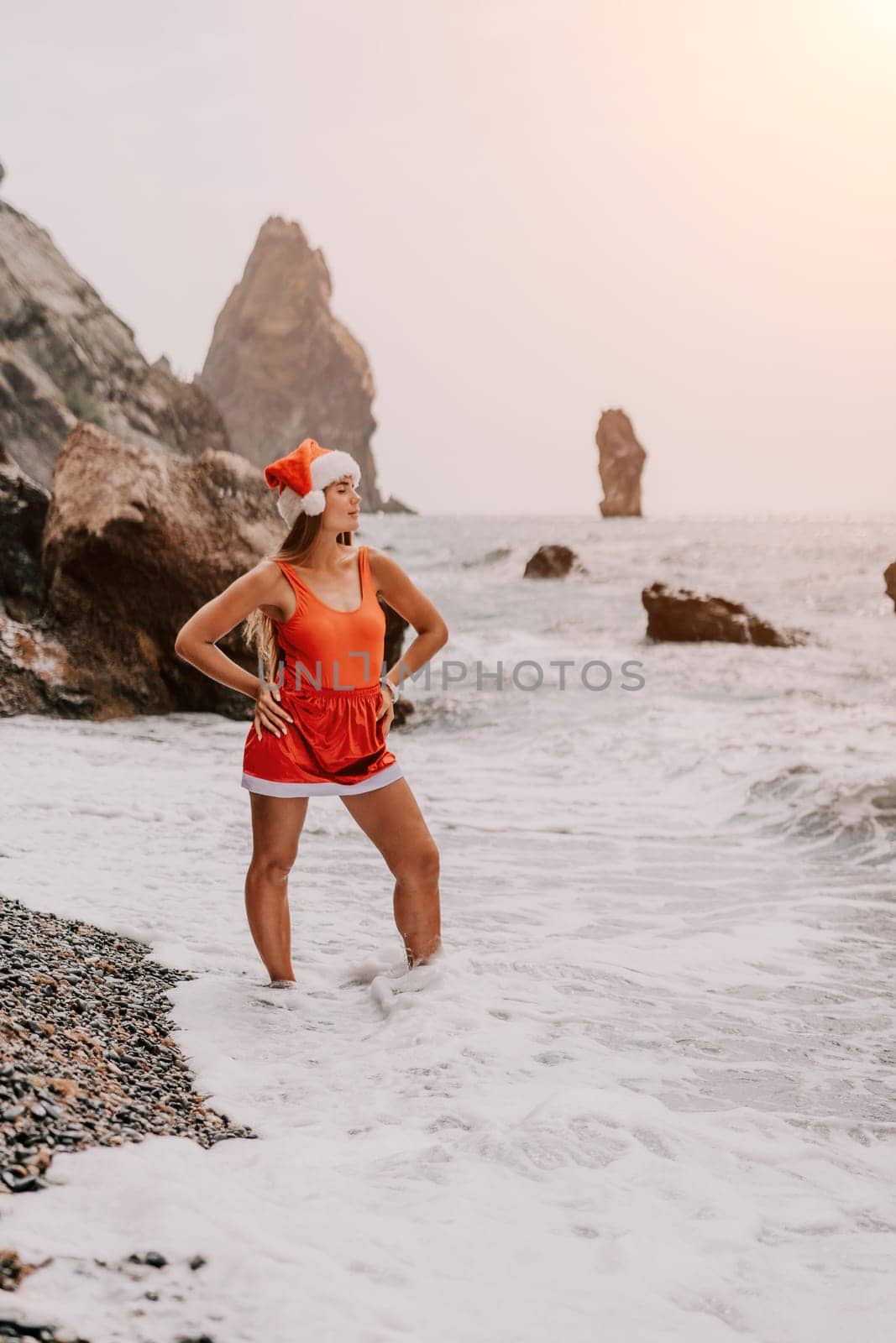 Woman travel sea. Young Happy woman in a long red dress posing on a beach near the sea on background of volcanic rocks, like in Iceland, sharing travel adventure journey