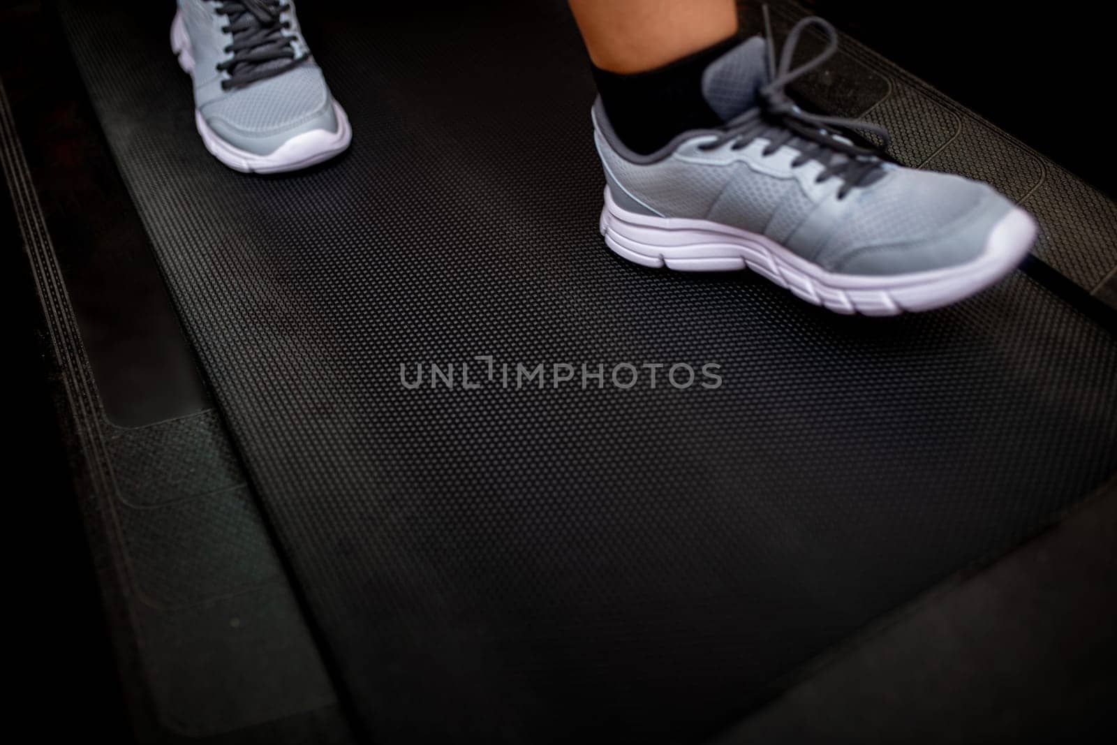 Feet of young girl running on treadmill. motion blur