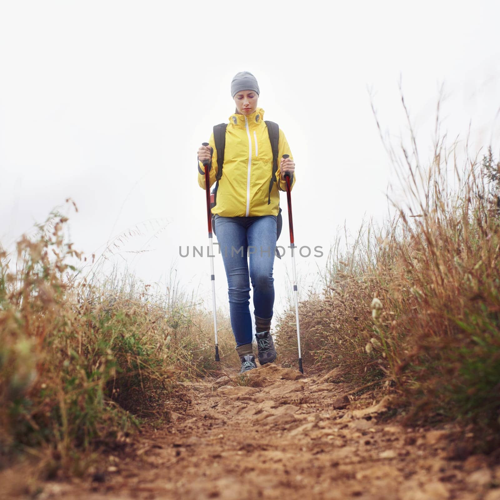 Hiking, woman and walking with trekking pole in a bush path or forest trail for exercise, workout or fitness on winter morning. Adventure, person or hiker in nature with backpack on holiday or travel by YuriArcurs