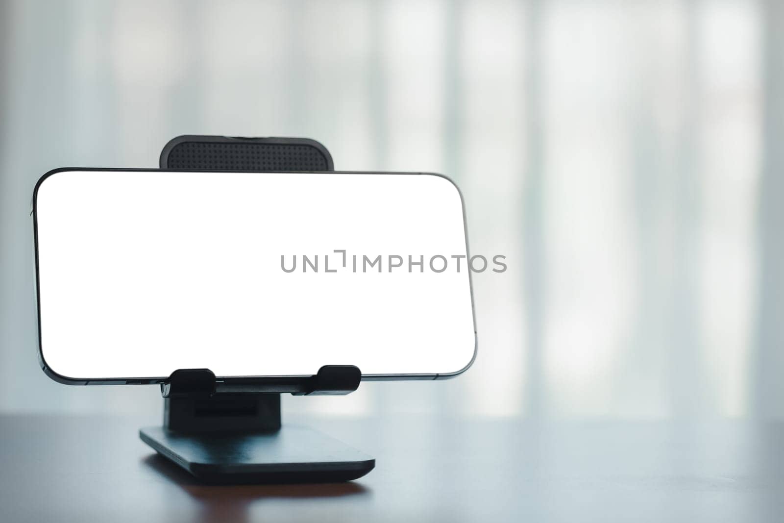 Blank white screen smartphone on wooden table with blur background in office room by iamnoonmai