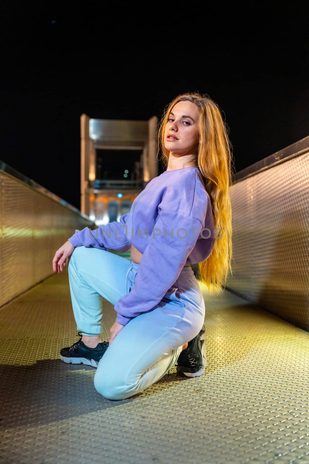 Blonde woman with urban hip hop style outdoors at night by Huizi