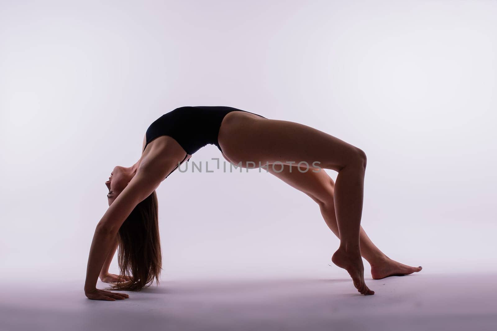 Young beautiful female yoga posing on gray studio background