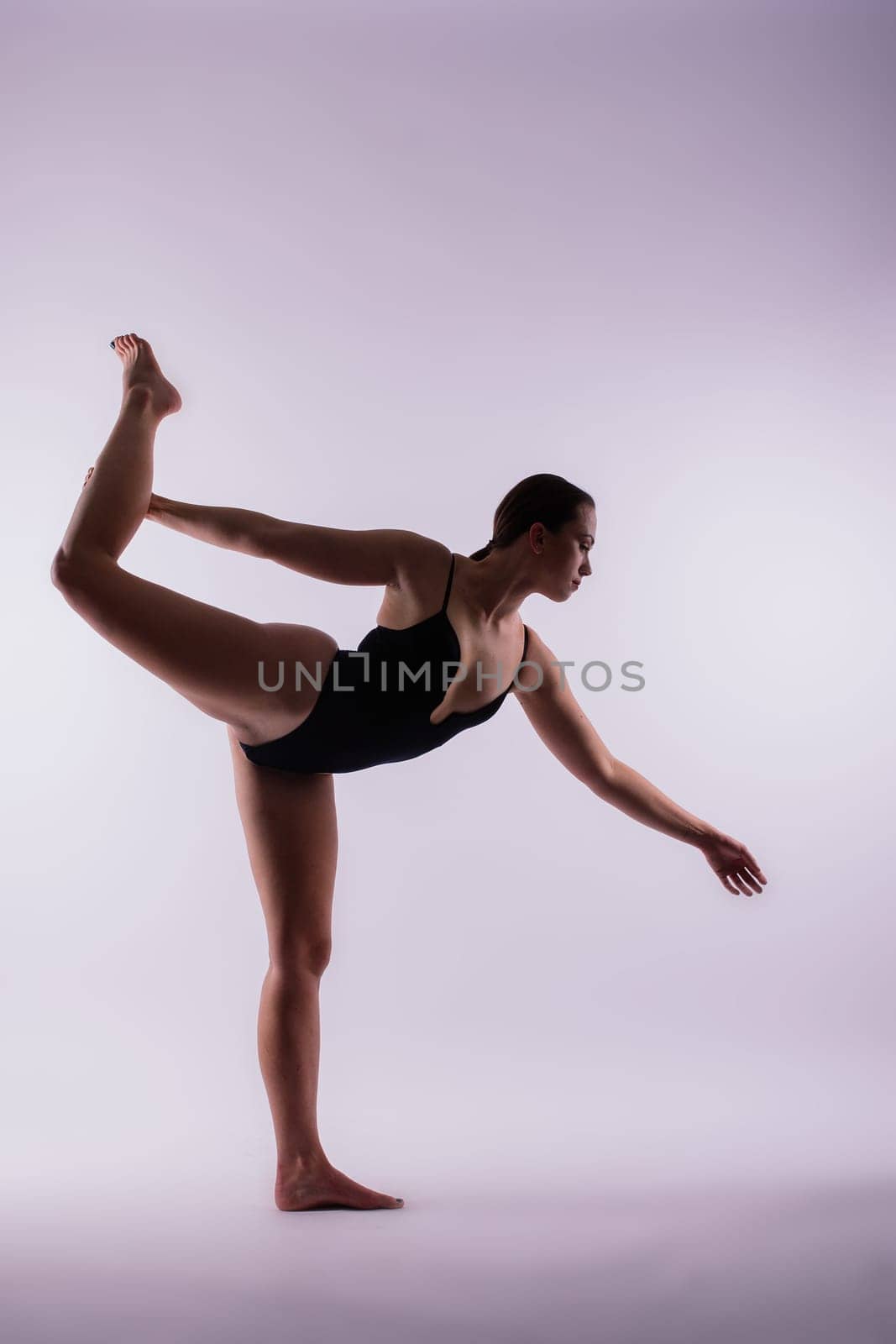 Young beautiful female yoga posing on a gray studio background by Zelenin