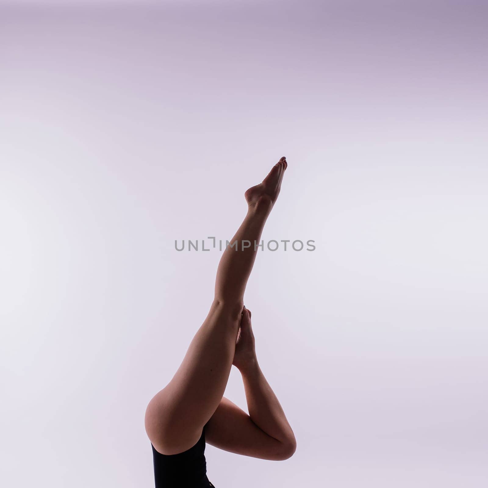 Young beautiful female yoga posing on a gray studio background by Zelenin