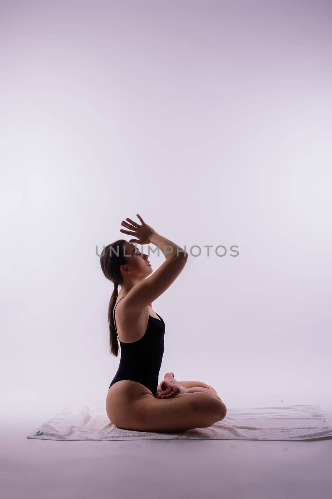 Young beautiful female yoga posing on a gray studio background by Zelenin