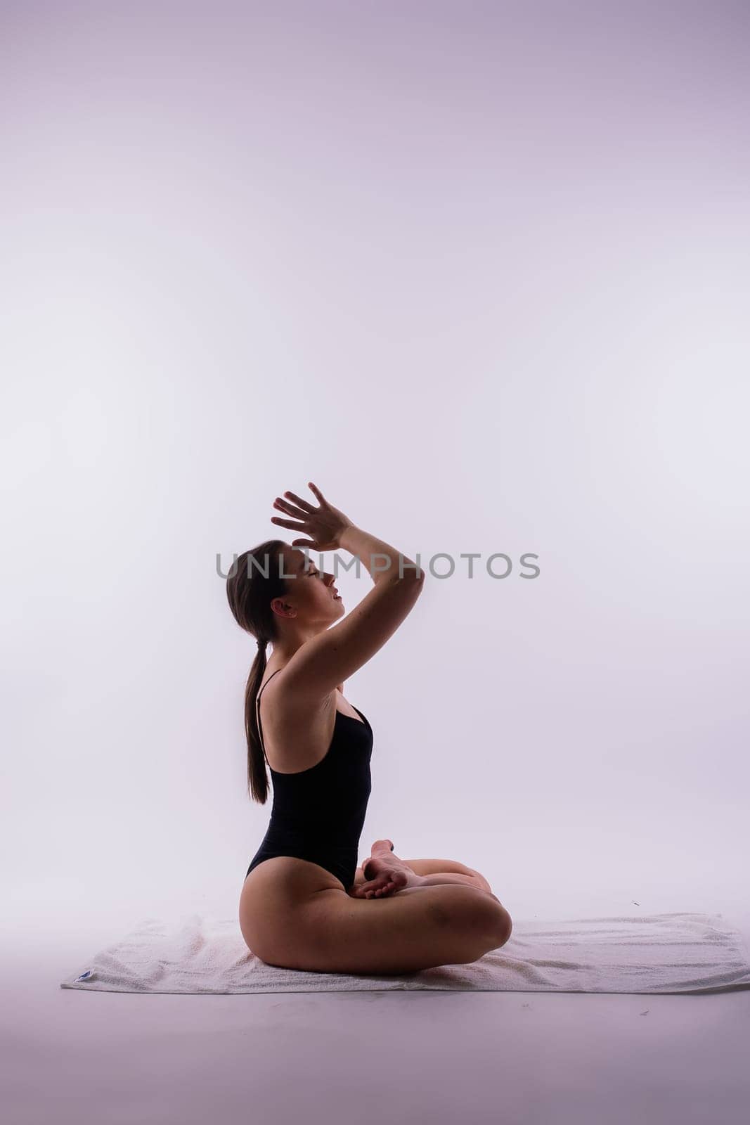 Young beautiful female yoga posing on gray studio background