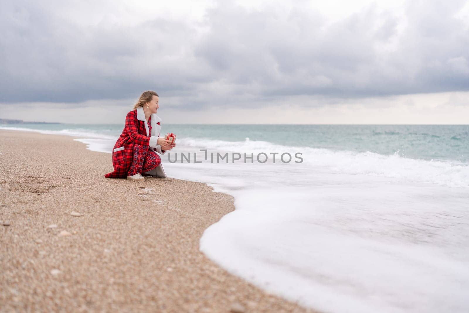 Lady in plaid shirt holding a gift in his hands enjoys beach with Christmas tree. Coastal area. Christmas, New Year holidays concep.