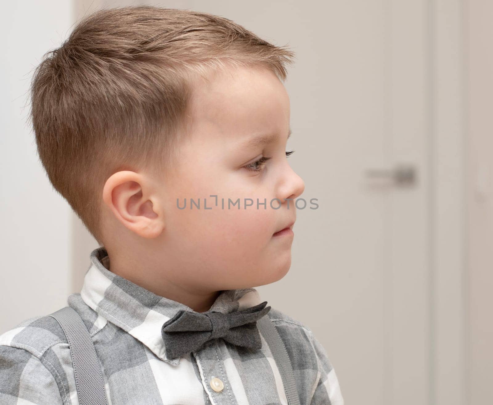 Emotions of calm, thoughtfulness on the child s face. A small handsome boy of 4 years old in a shirt with a bow tie shows a mime with a facial expression. Close-up. portrait
