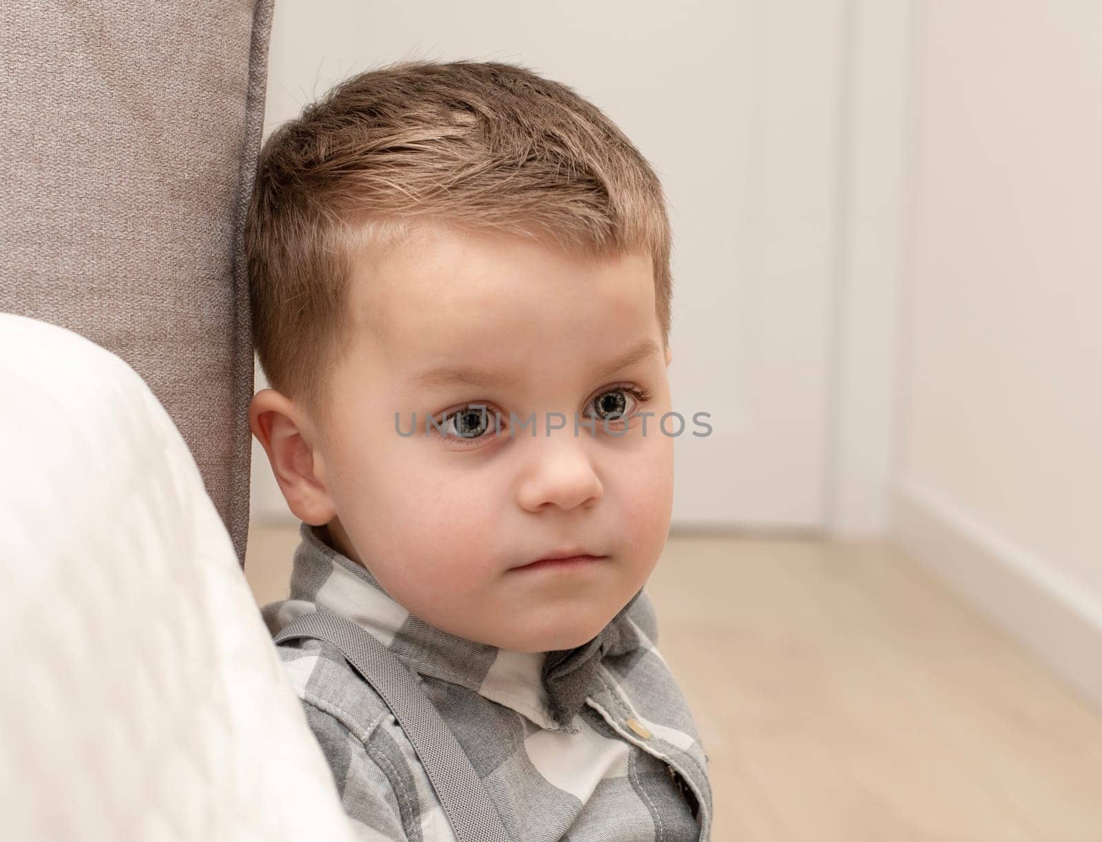 Emotions of calm, thoughtfulness on the child s face. A small handsome boy of 4 years old in a shirt with a bow tie shows a mime with a facial expression. by ketlit