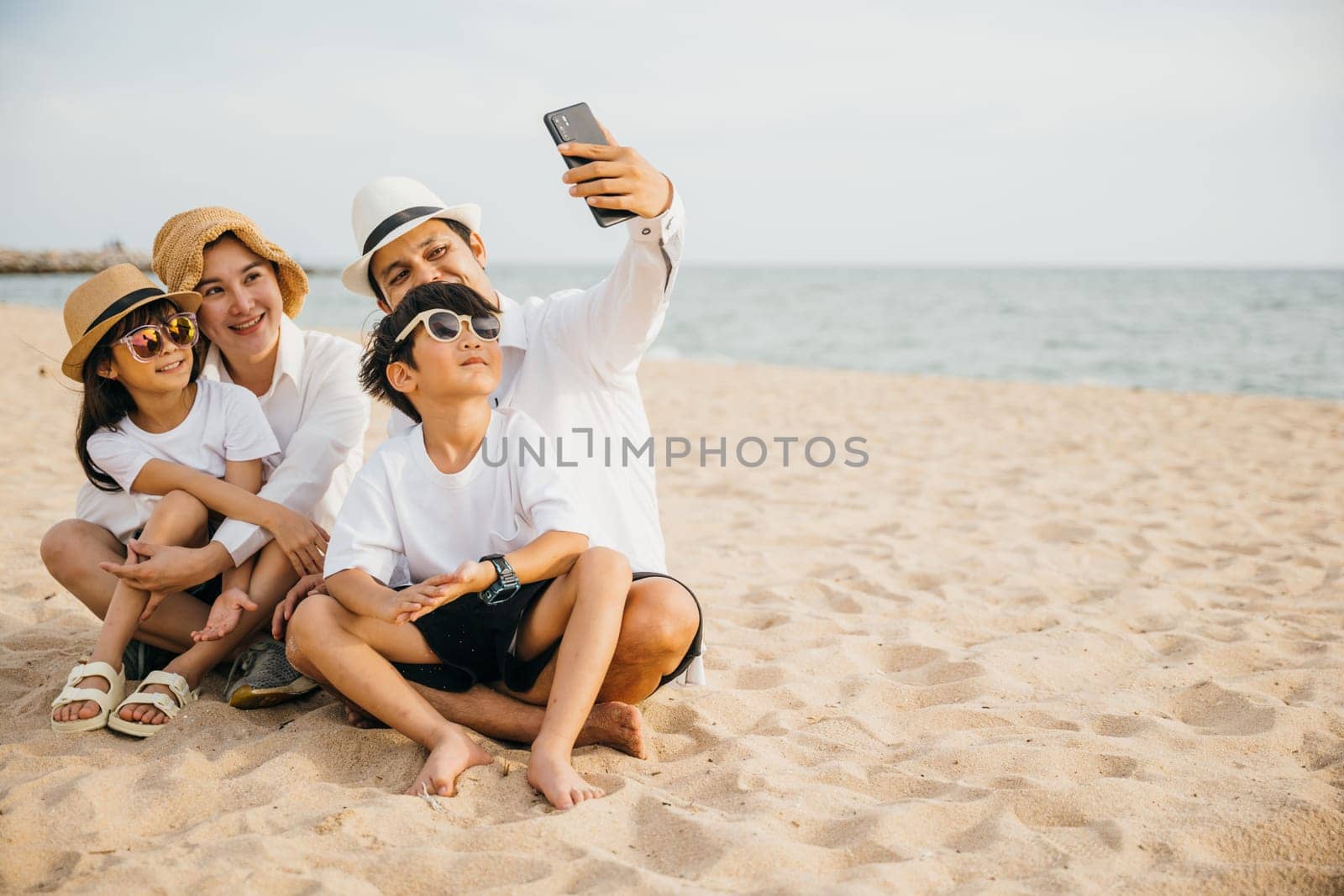 Summer joy on display as a happy family takes a lively selfie on the beach near the sea. Laughter smiles and the warmth of togetherness make this portrait a perfect capture of family happiness.