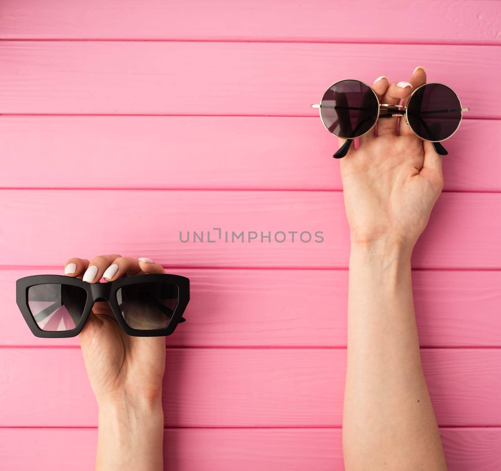 Summer abstract background mockup template free copy space for text pattern sample top view above on pink wooden board. blank empty area for inscription woman hands hold Couple sunglasses fashionable