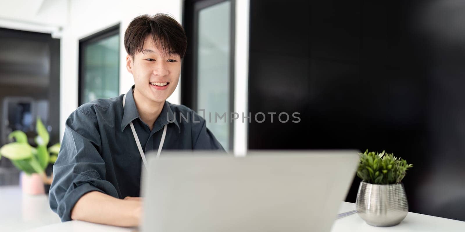 Businessman using laptop computer in office, Happy young asian businessman in modern office looking on laptop.