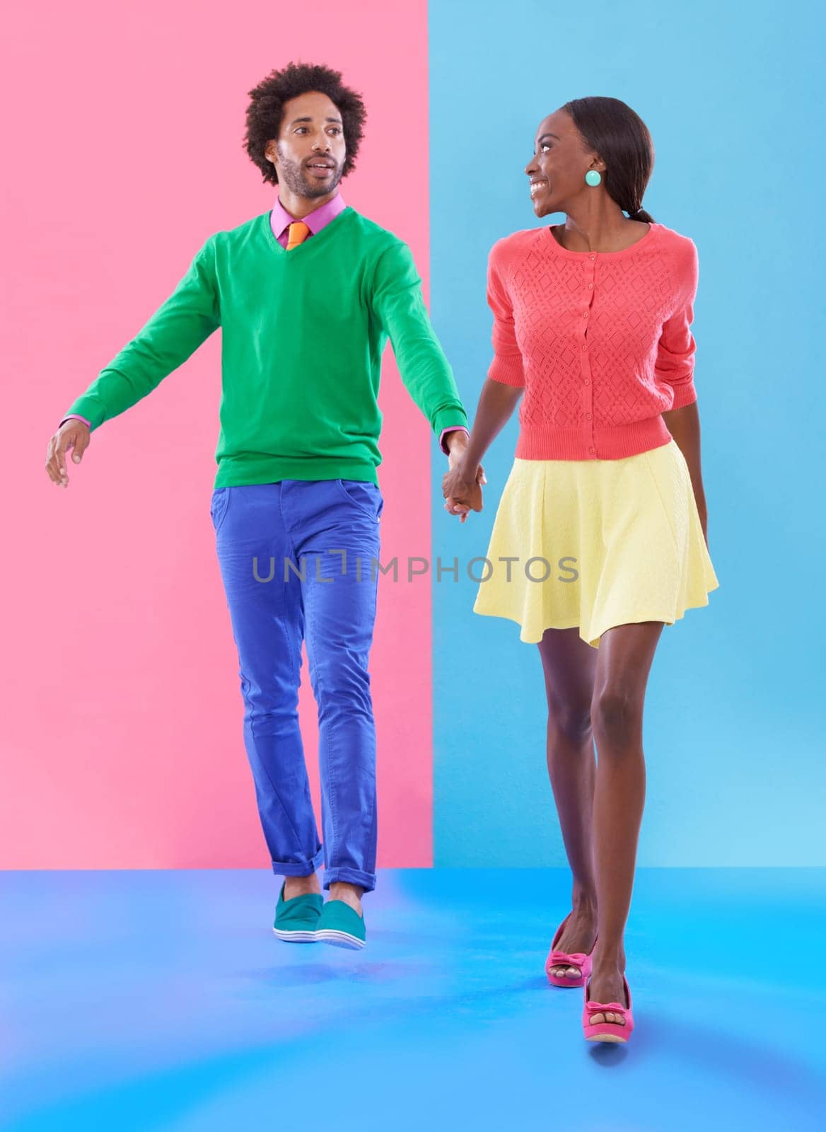 Couple, walk and holding hands with fashion in studio, background and creative aesthetic. Happy, woman and man together with colorful retro style, unique clothes or person with support or trust.