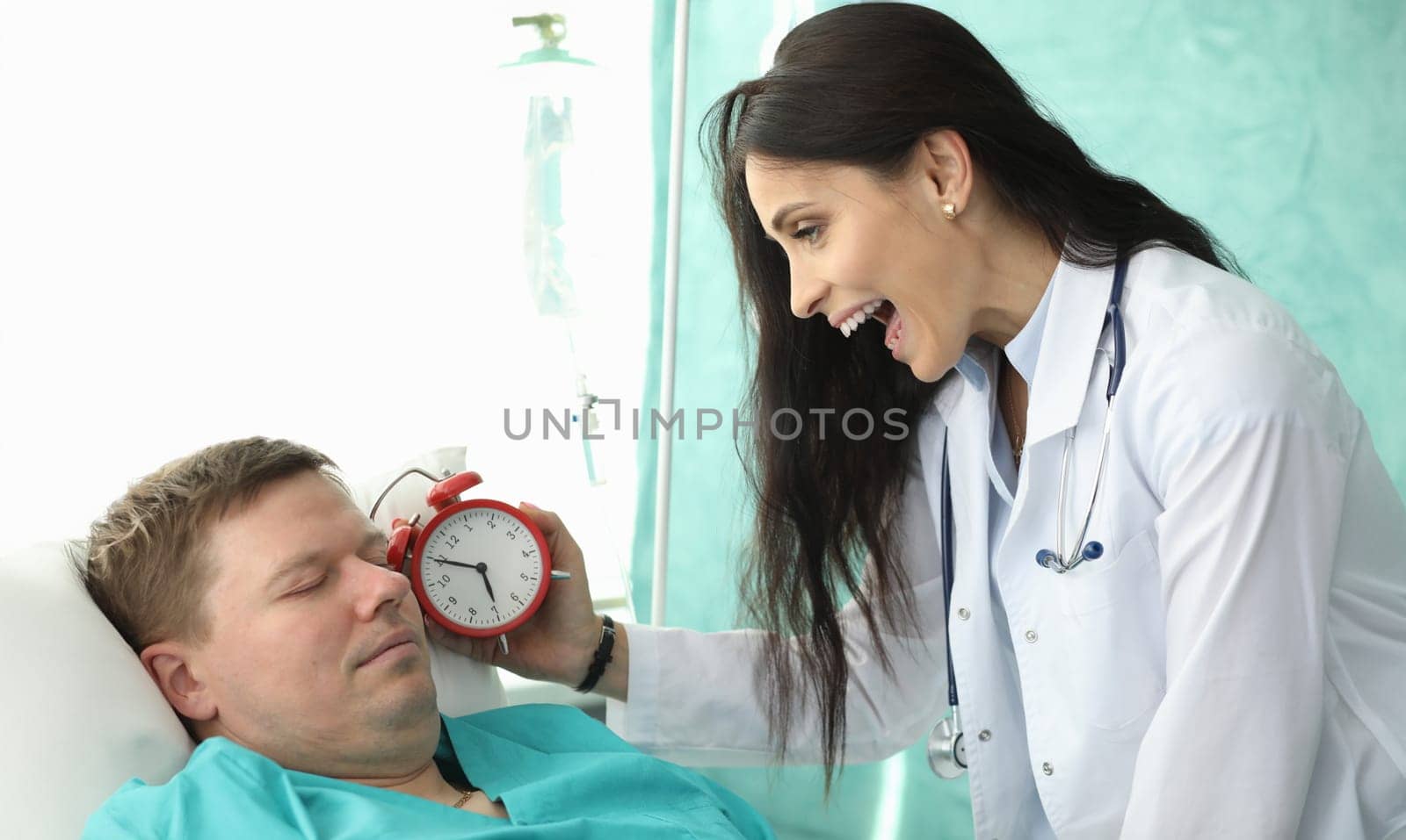 Nurse holds an alarm clock near patients face by kuprevich