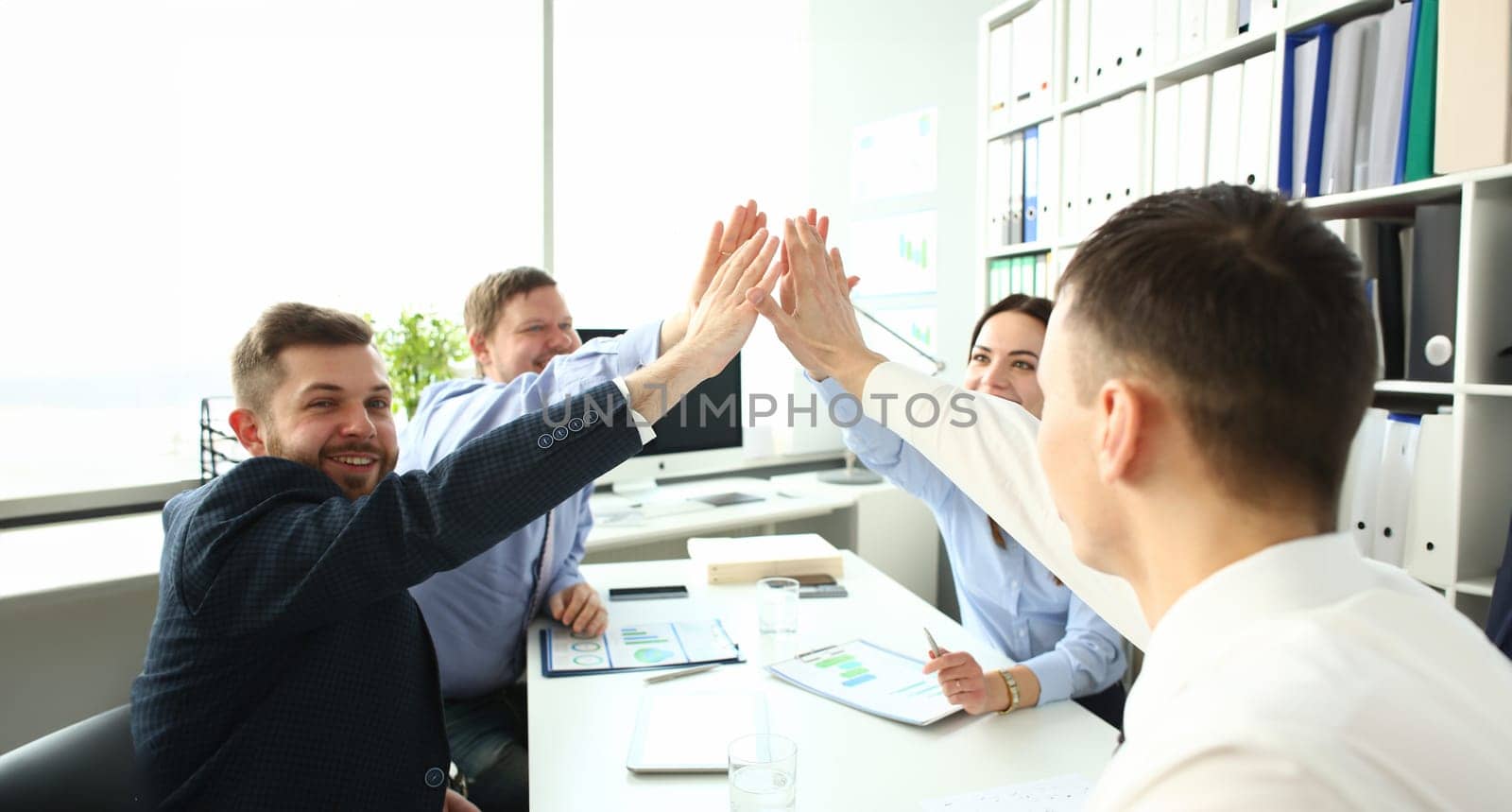 Group of businessman and businesswoman celebrating victory and teamspirit giving high five in air closeup