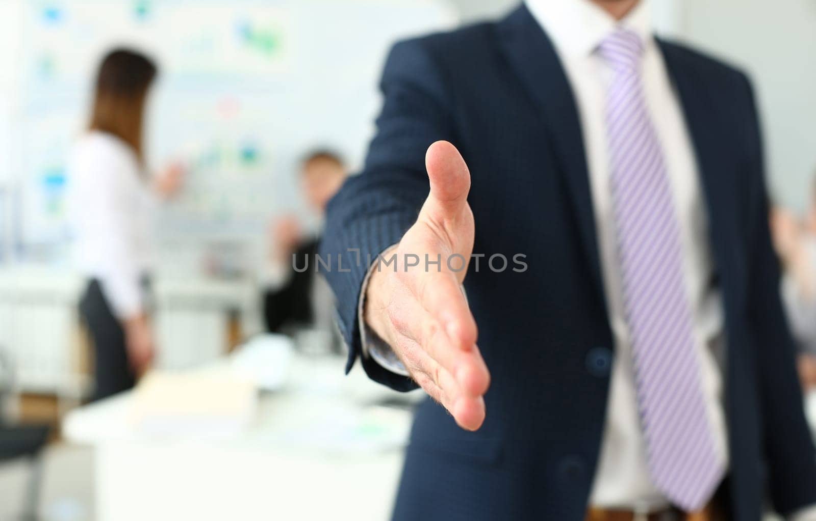 Businessman in suit and tie offering hand to shake to visitor by kuprevich