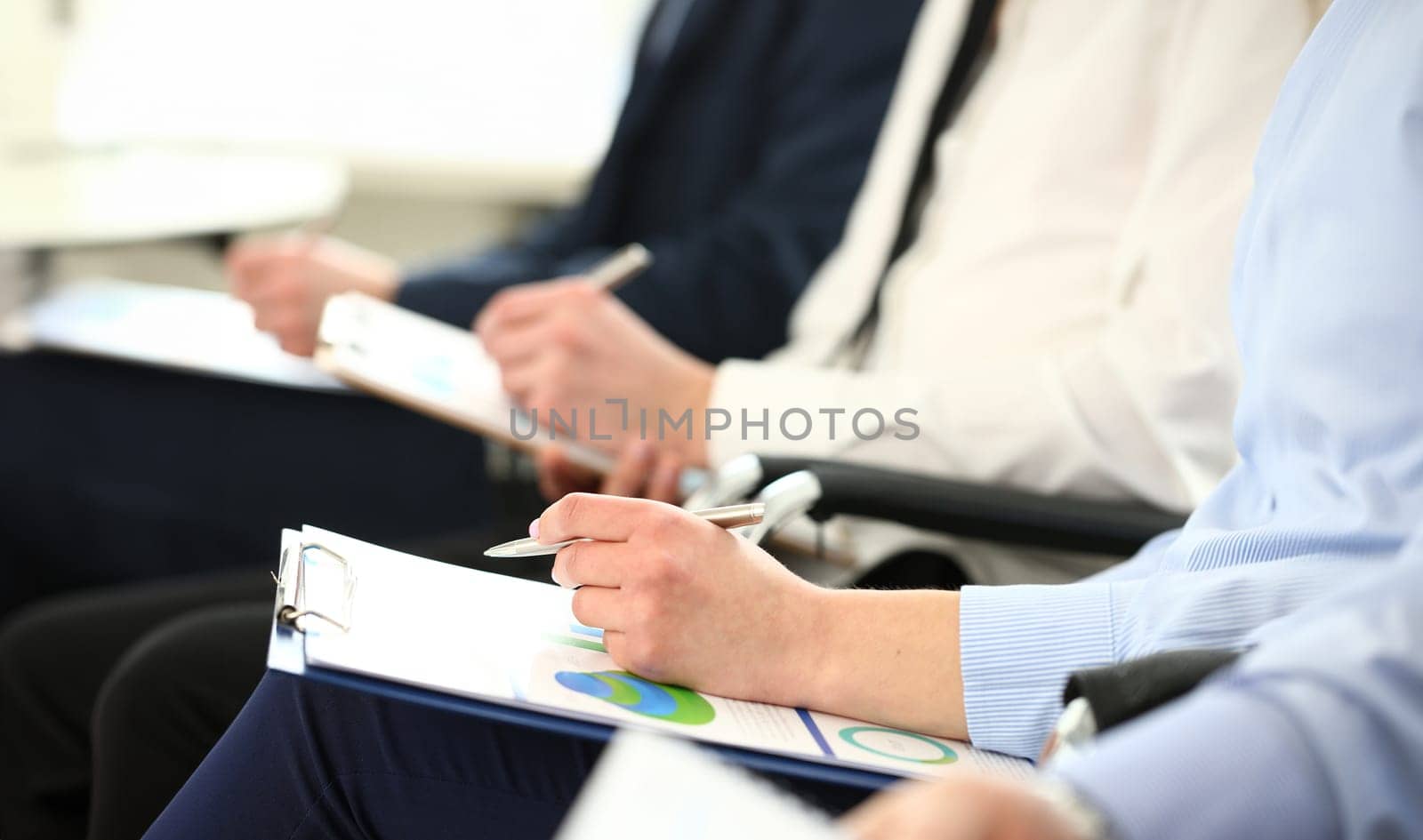 Hand holding silver pen and clipboard pad with statistics document by kuprevich