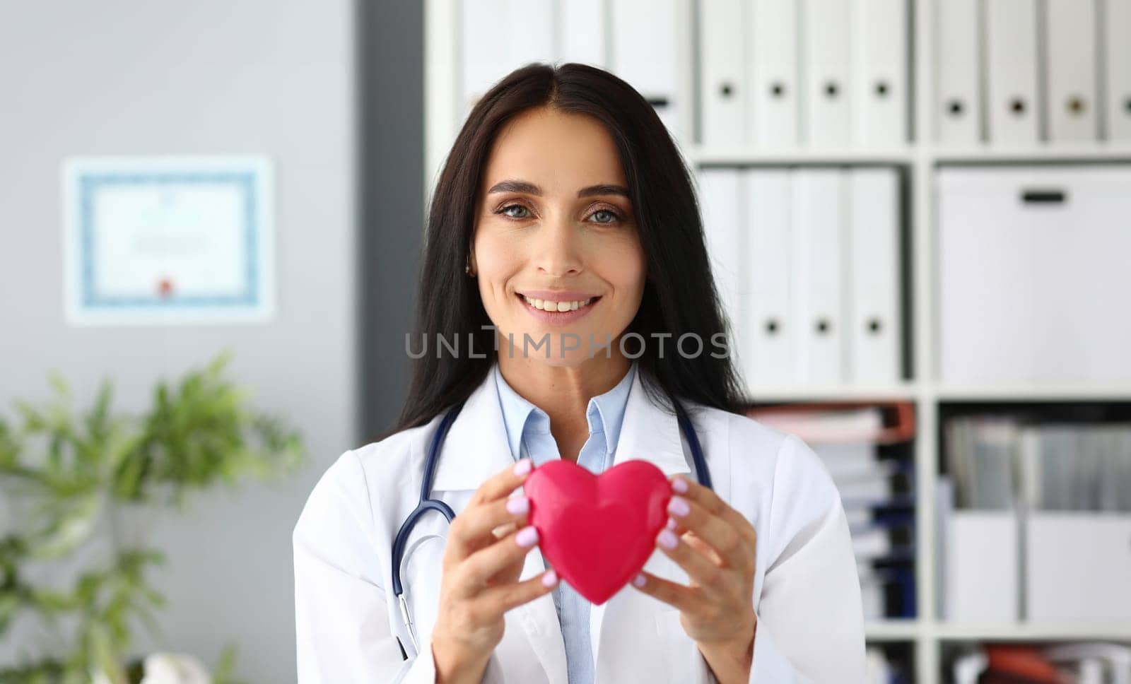 Beautiful smiling GP holding in hands red toy heart near chest portrait