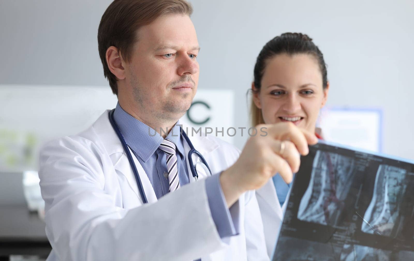 Male and female doctors carefully look at an x-ray by kuprevich