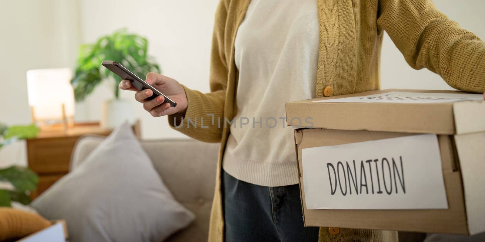 Donation concept. Woman asian holding a donate box with full of clothes. Woman holding clothes donate box. Clothes in box for concept donation and reuse recycle.