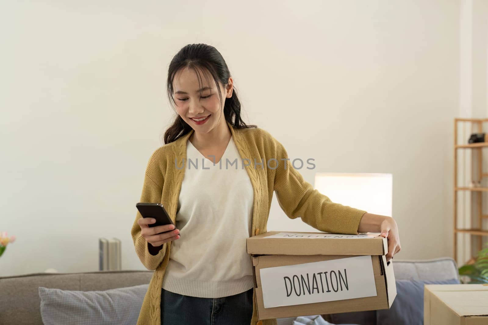 Donation concept. Woman asian holding a donate box with full of clothes. Woman holding clothes donate box. Clothes in box for concept donation and reuse recycle by nateemee