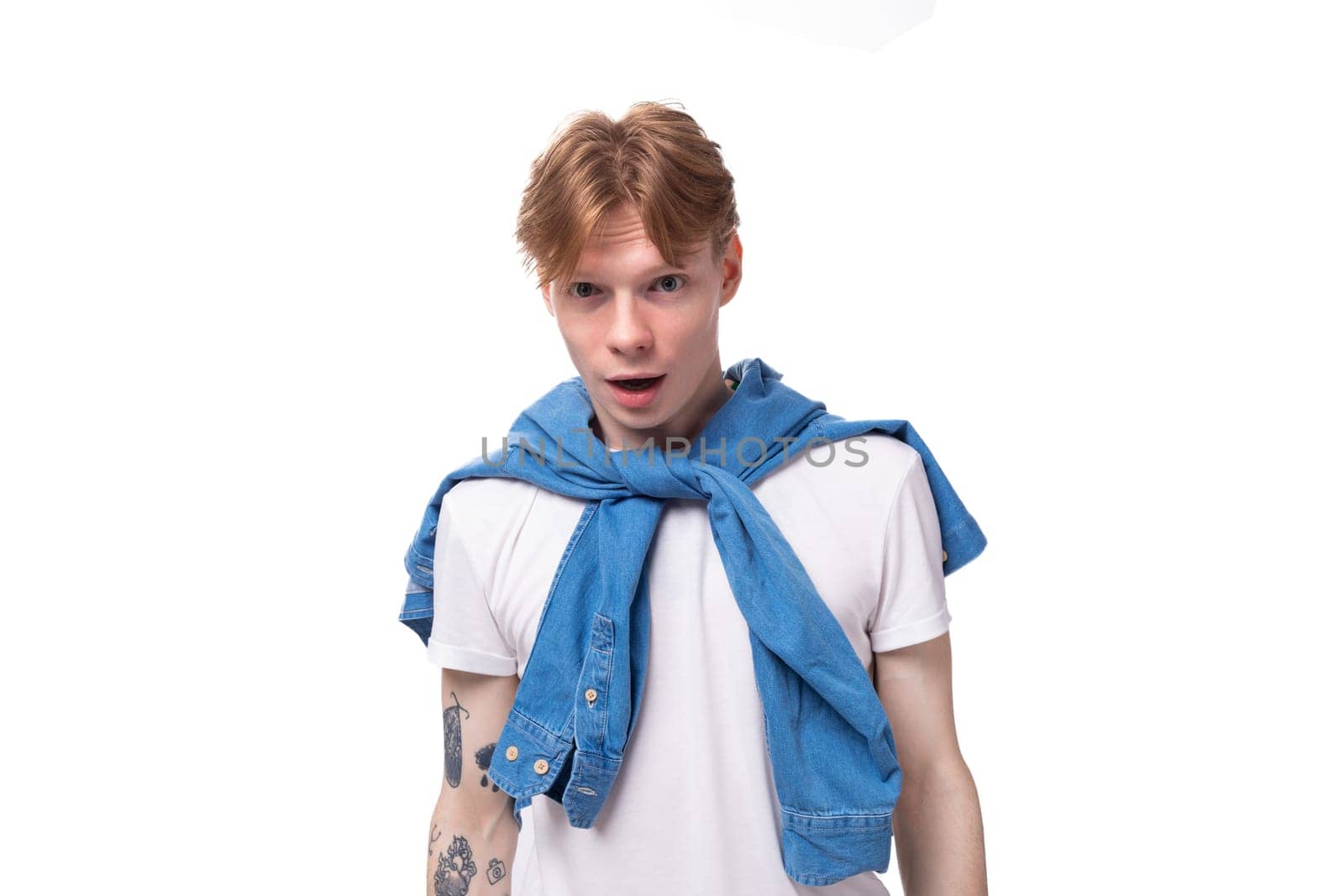 young short-haired caucasian male student with golden red hair with a tattoo on his arms is dressed in a white t-shirt by TRMK