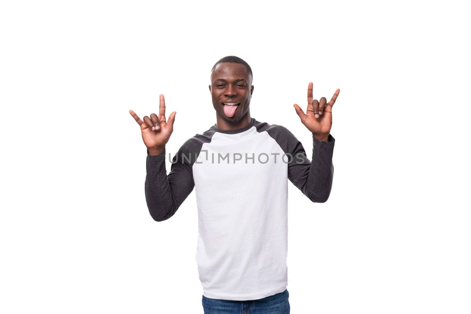 young stylish confident american man dressed casually in a black and white sweatshirt with long sleeves makes a grimace and shows his tongue by TRMK