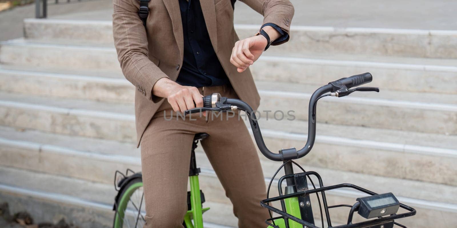 Asian businessman in a suit is riding a bicycle on the city streets for his morning commute to work. Eco transportation concept, sustainable lifestyle concept.