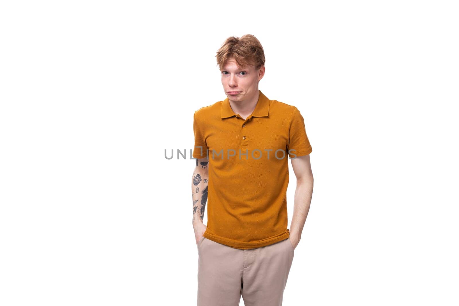 portrait of a young adorable redhead man dressed in a yellow t-shirt on a white background with copy space.