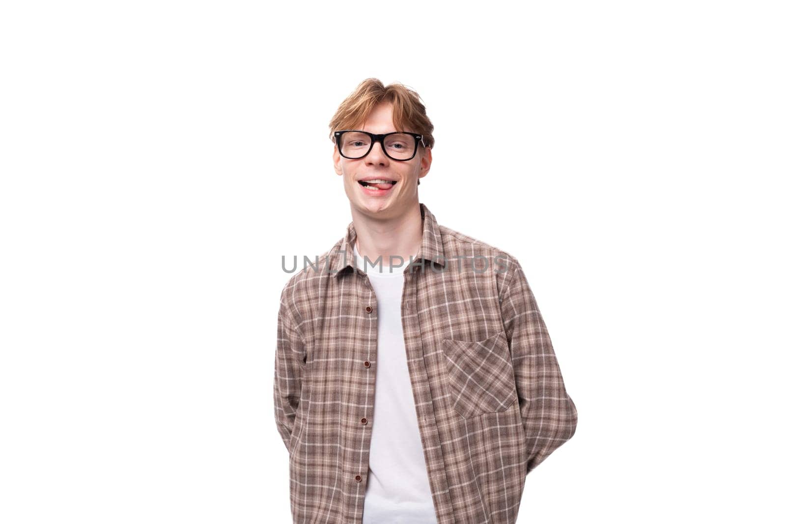 a young smiling man with red golden hair in glasses and a shirt stands alone on a white background.