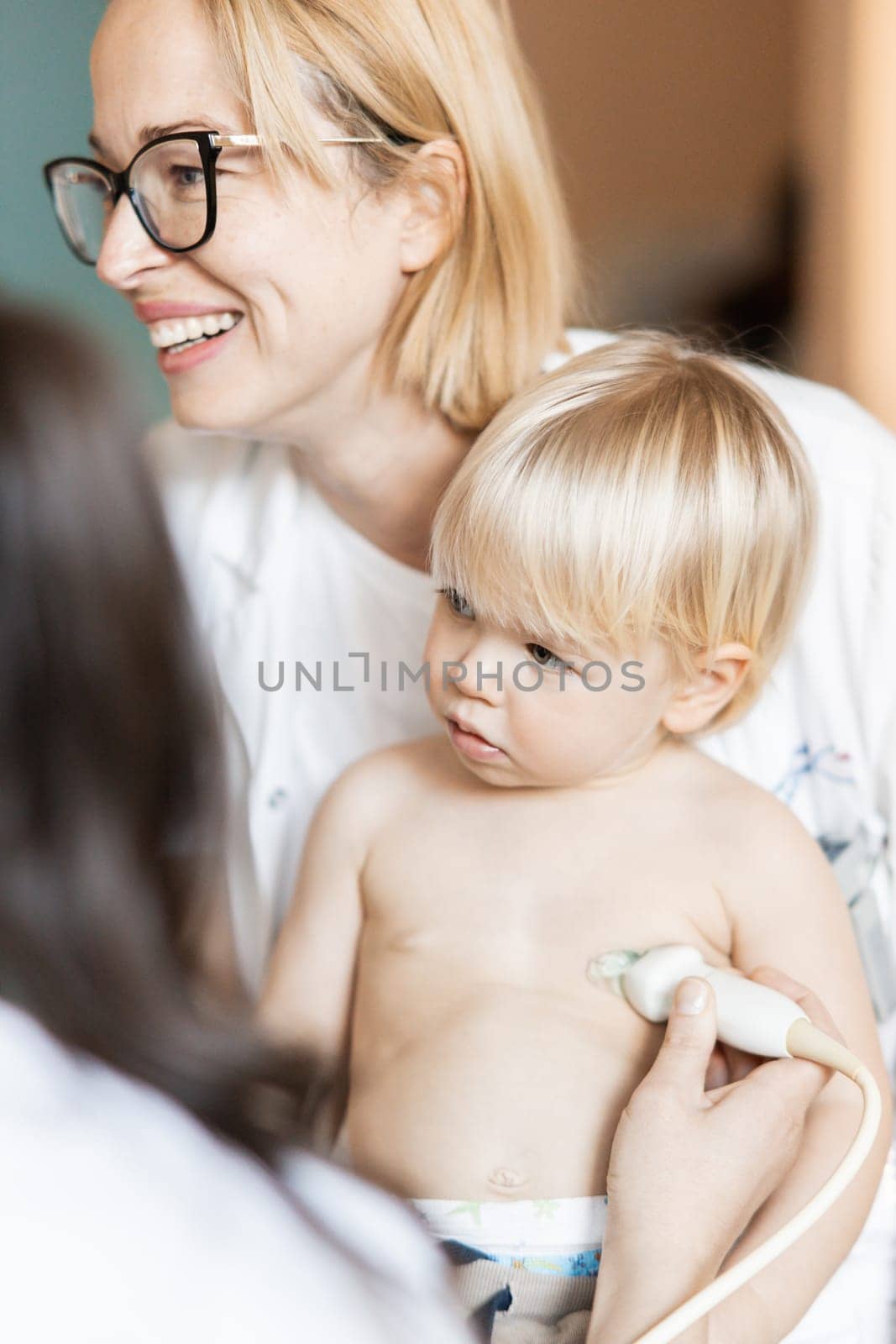 Small child being checked for heart murmur by heart ultrasound exam by cardiologist as part of regular medical checkout at pediatrician