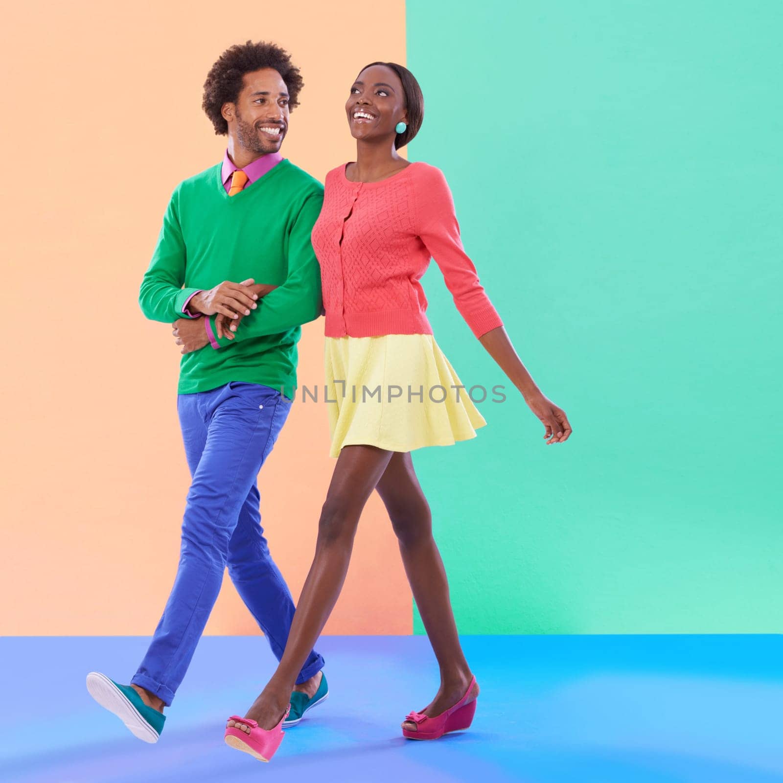Happy, couple and walk with fashion in studio, background and creative aesthetic. Excited, woman and man together with colorful retro style, unique clothes or person with support, love and trust by YuriArcurs