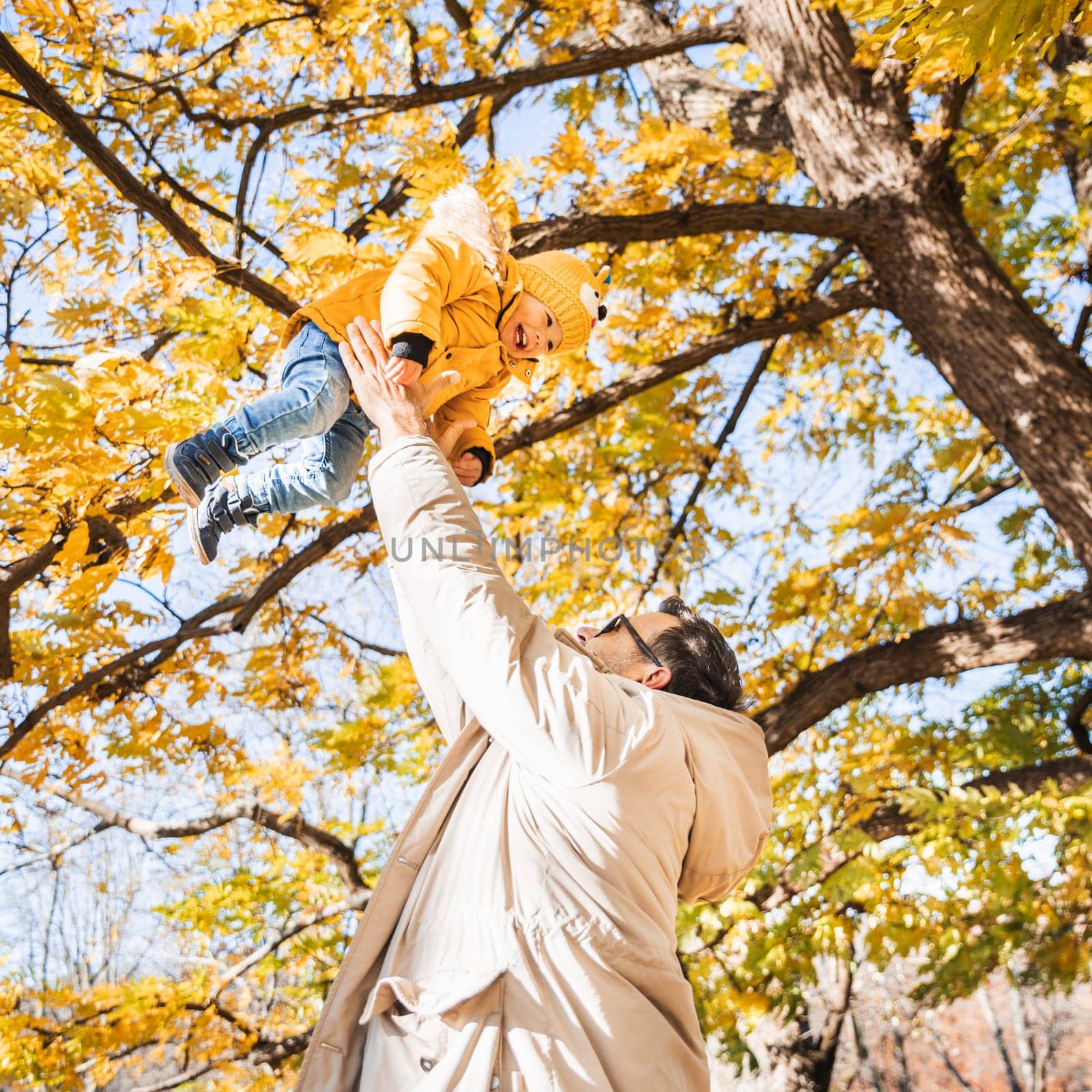 More, more,... dad, that's fun. Happy young father throws his cute little happy baby boy up in the air. Father's Day, Father and his son baby boy playing and hugging outdoors in nature in fall