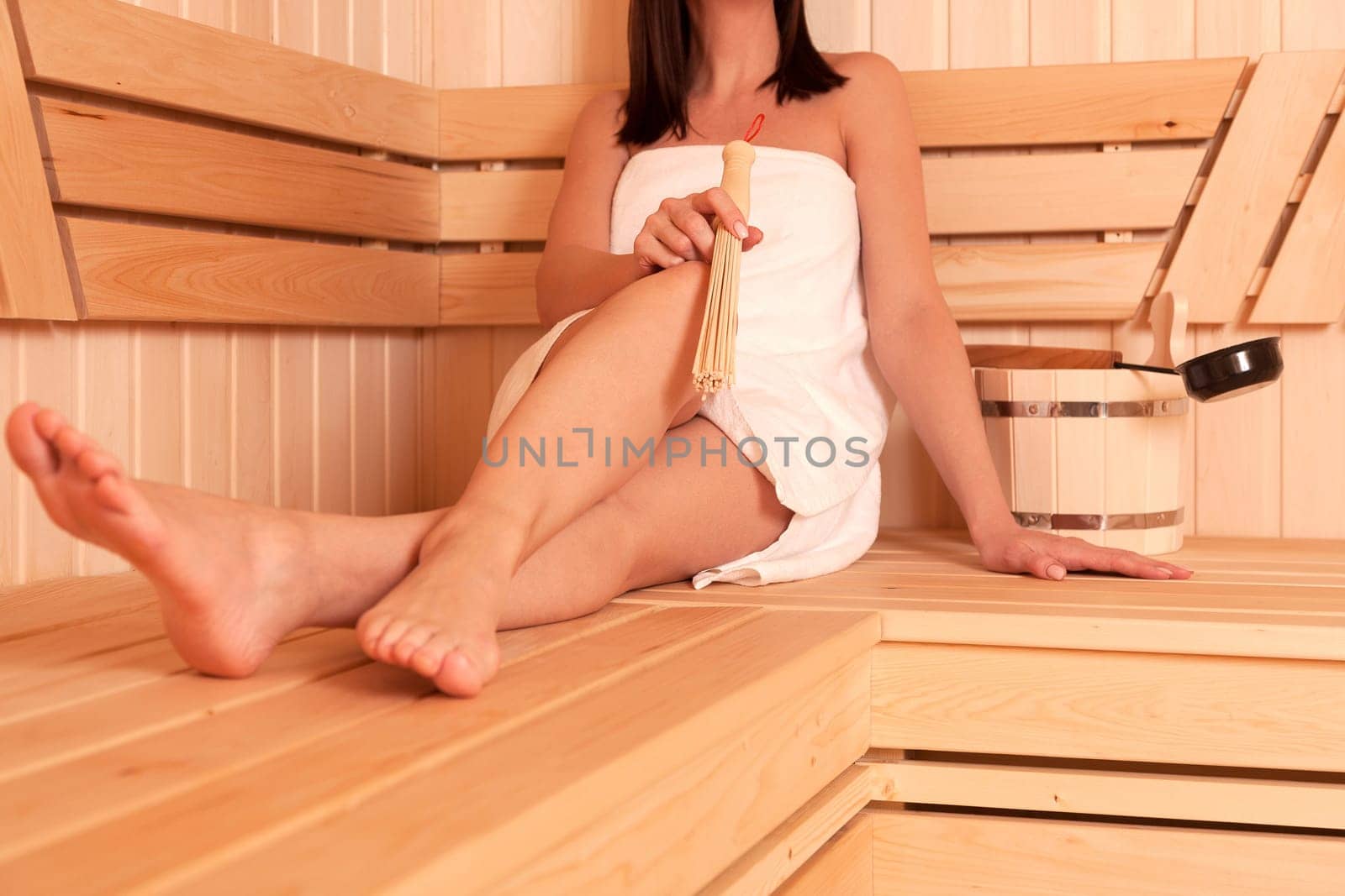 woman relaxing in a sauna and holding a tool for massage by Nobilior