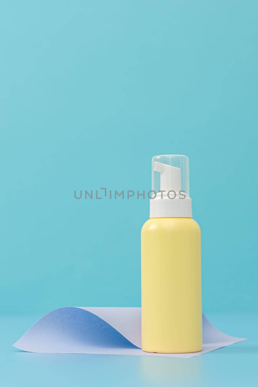 Yellow bottle with a dispenser on a blue background. by Nataliya